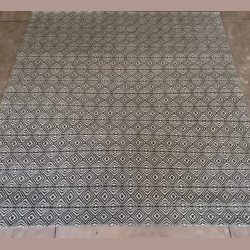 Patterned area rug with geometric designs on a tiled floor.
