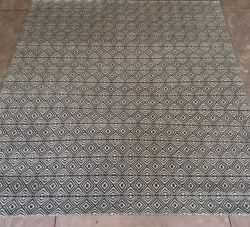 Patterned area rug with geometric designs on a tiled floor.