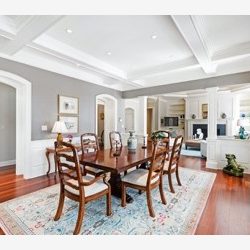 Elegant dining room with wooden table set for six, ornate chairs, white walls, hardwood floors, and a view into adjacent rooms.